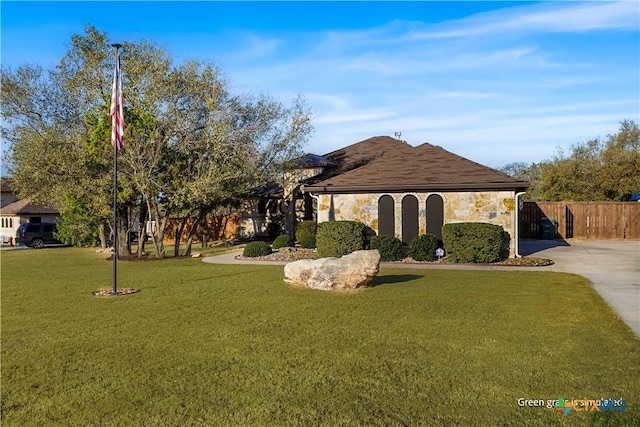 view of front of house featuring stone siding, driveway, a front yard, and fence