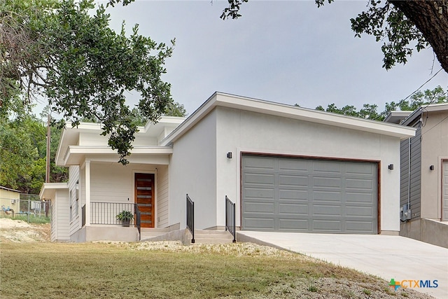 view of front of house featuring an attached garage, driveway, a front lawn, and stucco siding