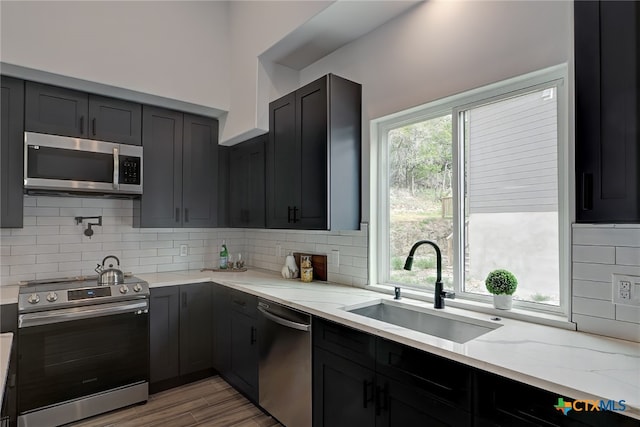 kitchen with stainless steel appliances, light stone countertops, plenty of natural light, and sink