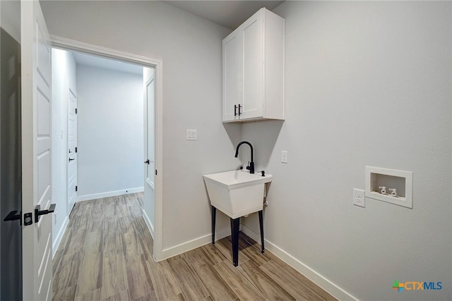 washroom with washer hookup, cabinets, and light hardwood / wood-style flooring