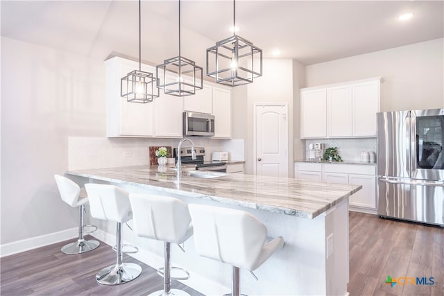 kitchen featuring kitchen peninsula, appliances with stainless steel finishes, decorative light fixtures, and white cabinets