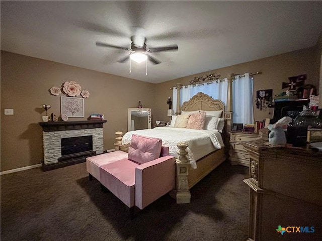 carpeted bedroom with a stone fireplace and ceiling fan