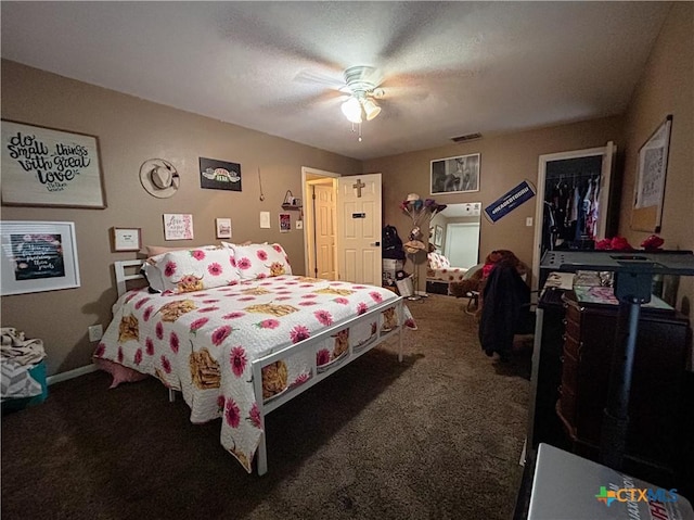 carpeted bedroom with a textured ceiling, a walk in closet, a closet, and ceiling fan