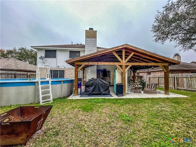 rear view of property with a yard, a fenced in pool, and a patio