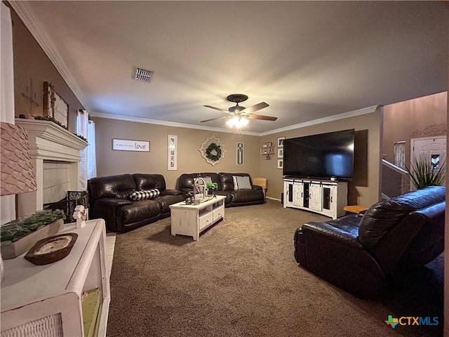 living room featuring ceiling fan, ornamental molding, carpet floors, and a tile fireplace