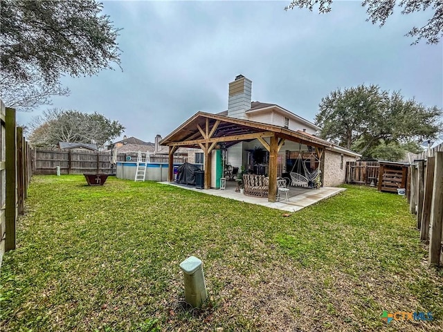 rear view of property featuring a yard, a fenced in pool, and a patio area