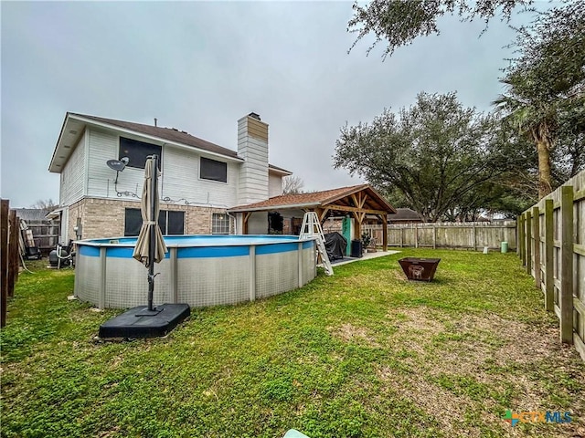 back of property with a fenced in pool, a gazebo, and a lawn