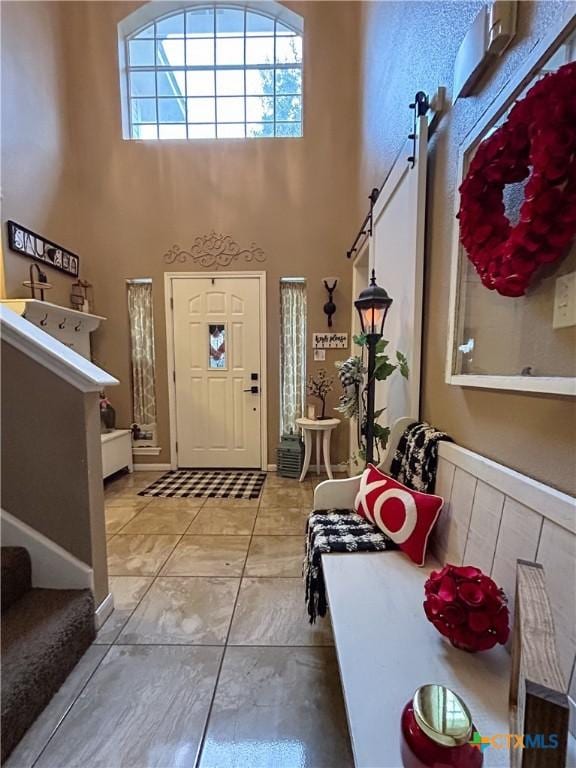 entryway with a towering ceiling and tile patterned floors