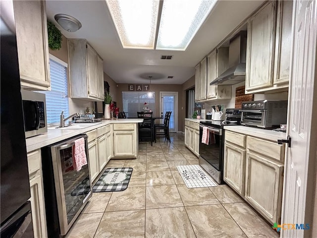 kitchen featuring sink, appliances with stainless steel finishes, wine cooler, cream cabinetry, and wall chimney exhaust hood