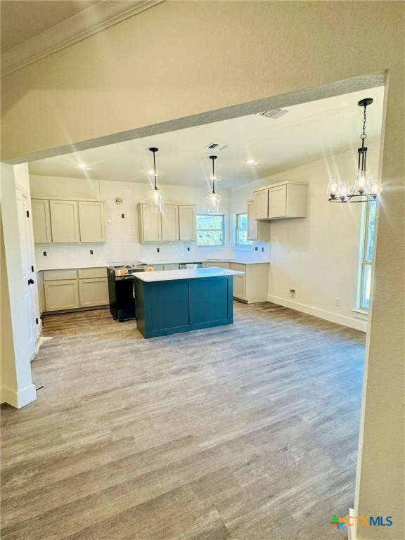 kitchen featuring an inviting chandelier, white cabinetry, a center island, hanging light fixtures, and light hardwood / wood-style floors