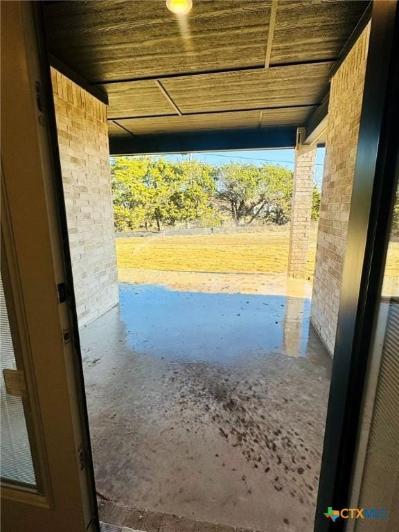 doorway to outside with wood ceiling and concrete flooring