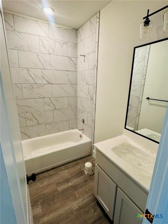 bathroom with vanity, hardwood / wood-style floors, and tiled shower / bath