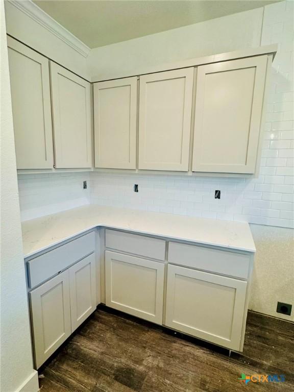 laundry area featuring dark wood-type flooring and crown molding