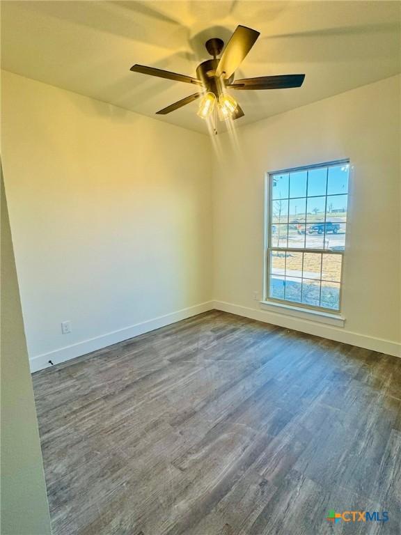 empty room featuring dark wood-type flooring and ceiling fan