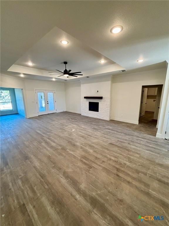 unfurnished living room featuring hardwood / wood-style flooring, ceiling fan, and a tray ceiling