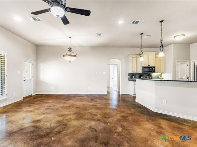 kitchen with stainless steel microwave, cream cabinets, dark countertops, and visible vents