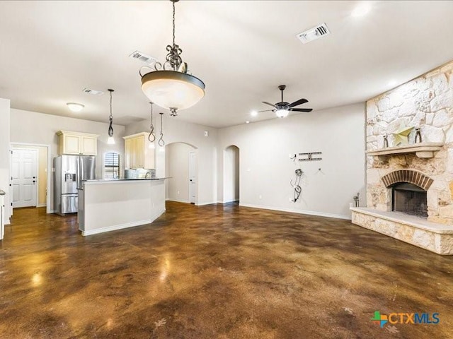 unfurnished living room featuring visible vents, a ceiling fan, a stone fireplace, arched walkways, and finished concrete floors