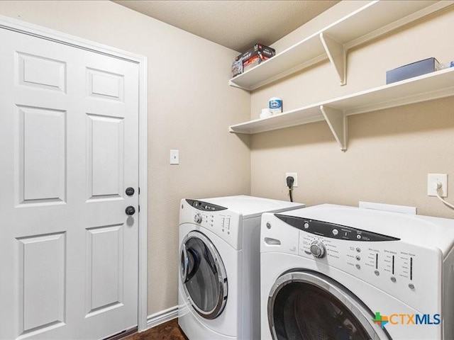 washroom featuring baseboards, separate washer and dryer, and laundry area