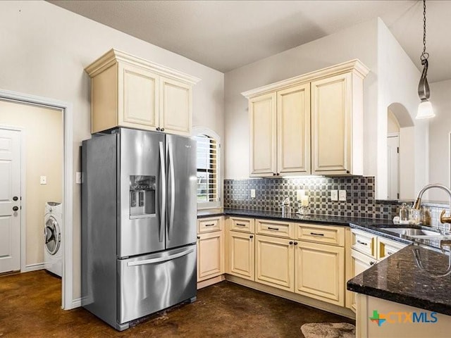 kitchen with stainless steel fridge, washer / clothes dryer, a sink, cream cabinets, and backsplash