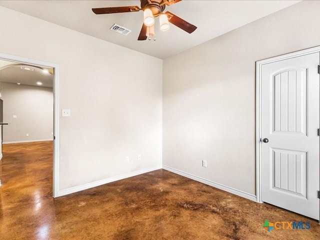 spare room featuring concrete flooring, baseboards, ceiling fan, and visible vents