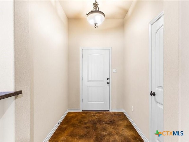 doorway to outside with unfinished concrete flooring and baseboards