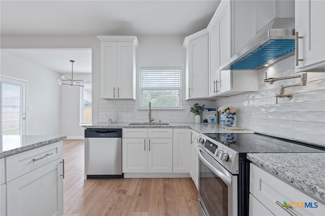 2534 Duval Dr, New Braunfels, TX 78130 - kitchen featuring stainless steel appliances, range hood, white cabinets, light wood-style flooring, and backsplash