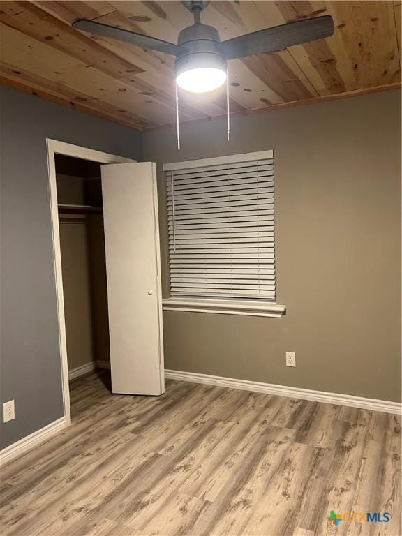 unfurnished bedroom featuring ceiling fan, wooden ceiling, a closet, and light wood-type flooring