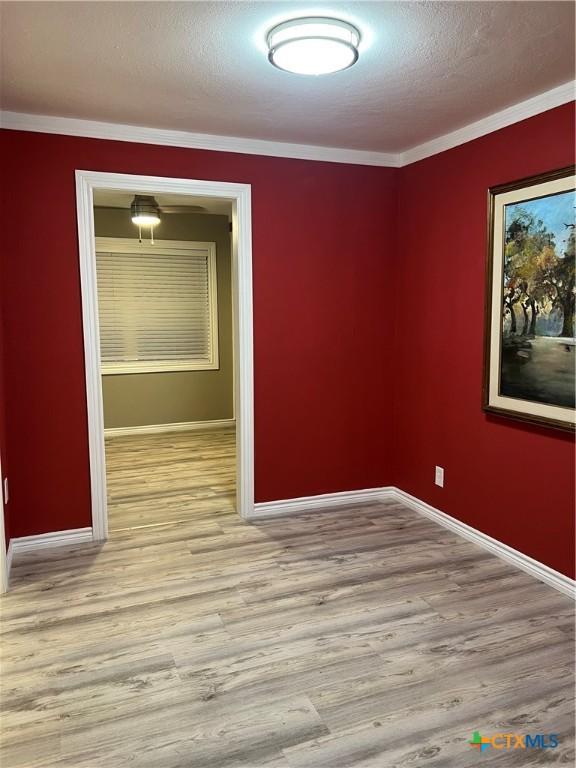 unfurnished room featuring light wood-type flooring, ornamental molding, and a textured ceiling