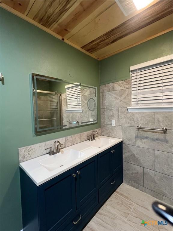 bathroom with wood ceiling, a shower with shower door, tile patterned flooring, tile walls, and vanity