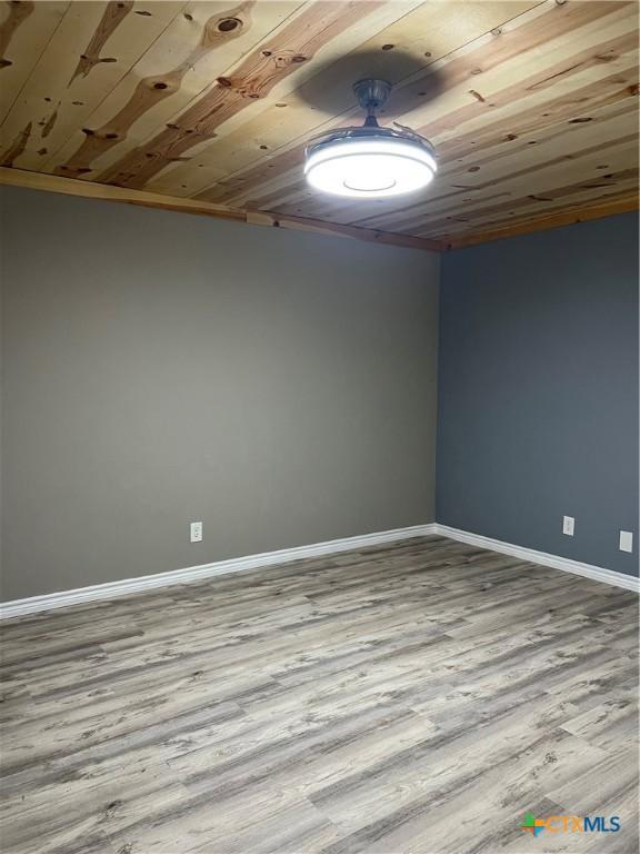 unfurnished room with light wood-type flooring, wooden ceiling, and ornamental molding