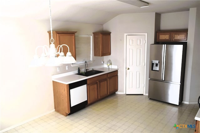 kitchen featuring vaulted ceiling, pendant lighting, dishwasher, sink, and stainless steel fridge