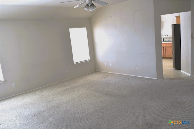 carpeted empty room with vaulted ceiling, sink, and ceiling fan