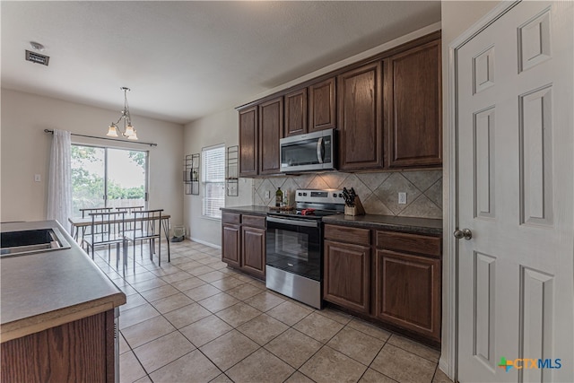 kitchen with dark brown cabinets, appliances with stainless steel finishes, light tile patterned flooring, and backsplash