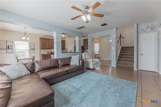 tiled living room featuring ceiling fan with notable chandelier