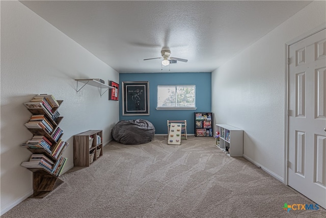 misc room with a textured ceiling, light carpet, and ceiling fan