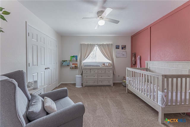 carpeted bedroom with a nursery area and ceiling fan