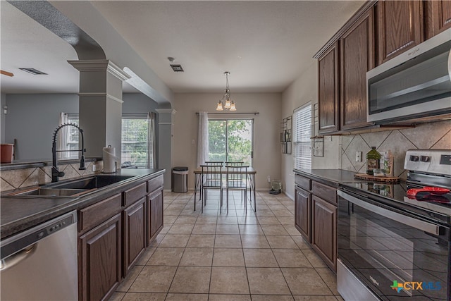 kitchen featuring stainless steel appliances, dark brown cabinets, sink, decorative backsplash, and decorative columns