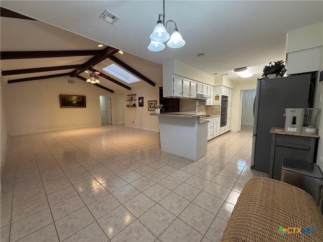 1001 Brookhollow Dr, Port Lavaca, TX 77979 - kitchen featuring light tile patterned floors, open floor plan, a peninsula, freestanding refrigerator, and a textured ceiling