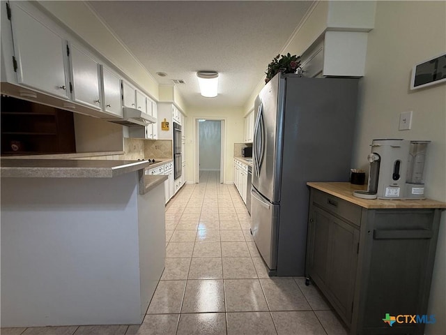 1001 Brookhollow Dr, Port Lavaca, TX 77979 - kitchen featuring stainless steel appliances, under cabinet range hood, light tile patterned floors, and a textured ceiling