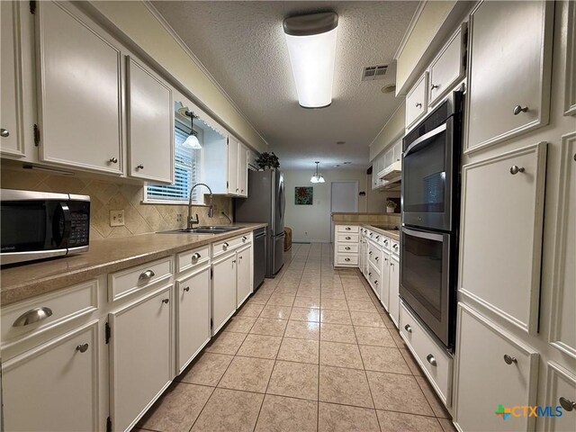 1001 Brookhollow Dr, Port Lavaca, TX 77979 - kitchen with stainless steel appliances, a textured ceiling, decorative backsplash, light tile patterned flooring, and white cabinets