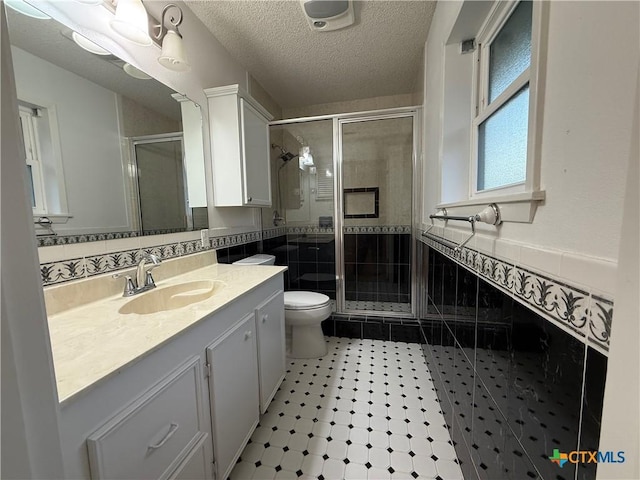 1001 Brookhollow Dr, Port Lavaca, TX 77979 - bathroom featuring vanity, a stall shower, a textured ceiling, a wainscoted wall, and tile walls