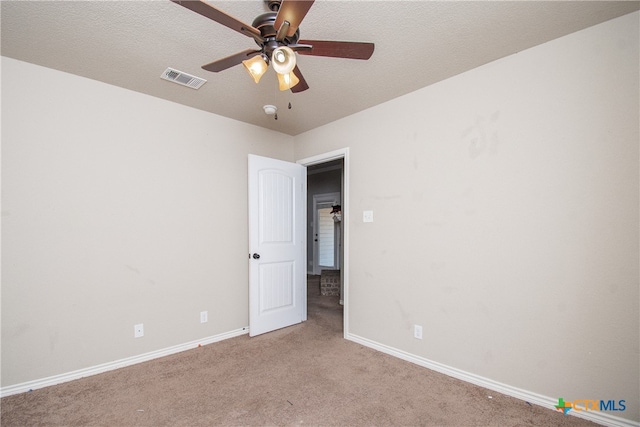 carpeted spare room with a textured ceiling and ceiling fan