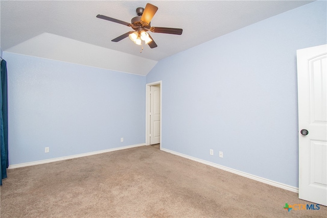 spare room featuring vaulted ceiling, light carpet, and ceiling fan