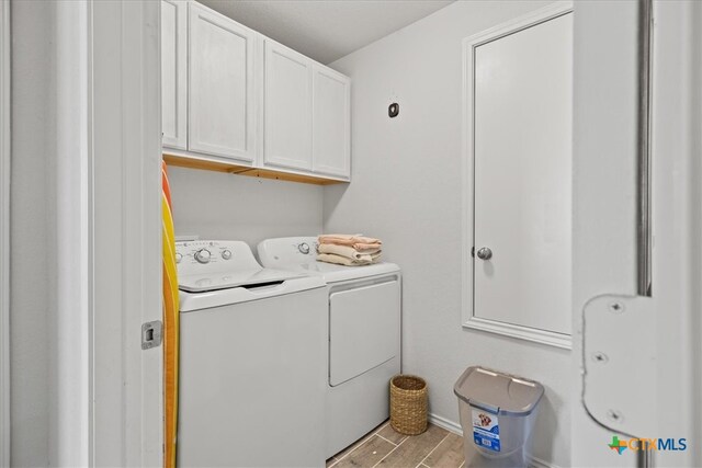 washroom featuring light wood-type flooring, cabinets, and washer and dryer