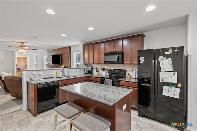 kitchen with black appliances, decorative backsplash, sink, ceiling fan, and a center island