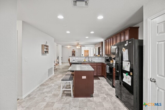 kitchen featuring sink, black appliances, kitchen peninsula, a kitchen breakfast bar, and a center island