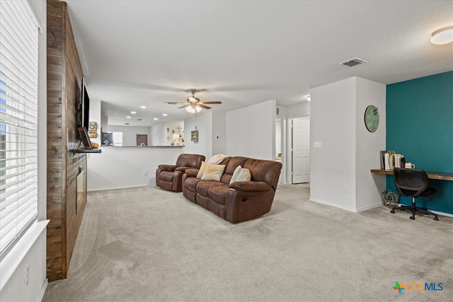 living room featuring built in desk, ceiling fan, and light carpet