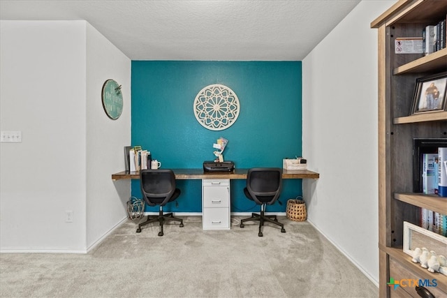 carpeted home office with a textured ceiling and built in desk