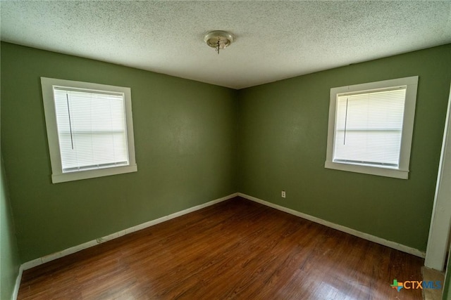 empty room with baseboards, wood finished floors, and a textured ceiling