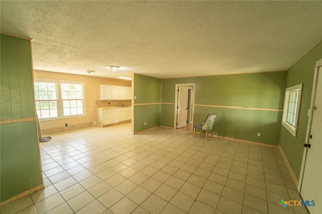 empty room featuring a textured ceiling, baseboards, and light tile patterned floors